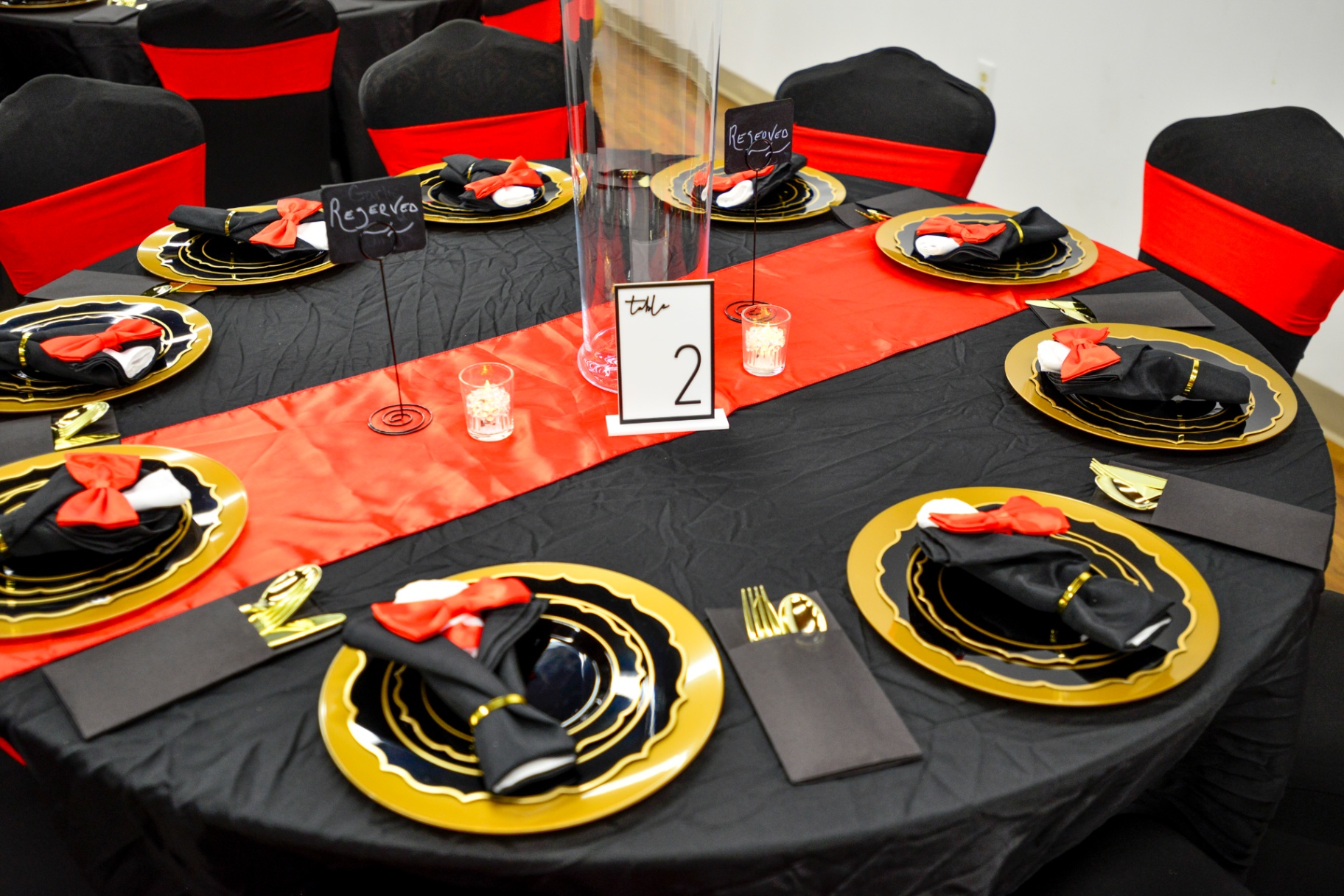 Overhead view of a table with black linen, red runner and gold chargers
