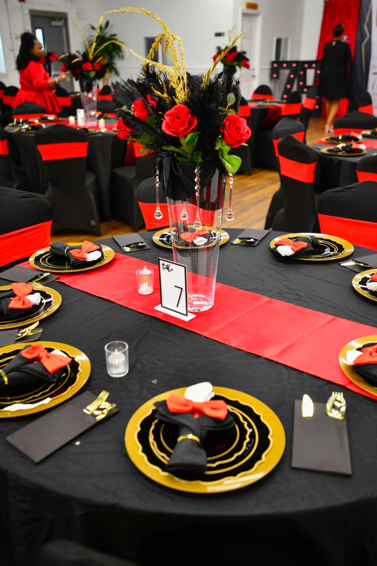 Table centerpiece with red roses, black feathers and gold accents